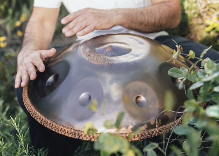 close-up front view of the hands of an unrecognizable man playing handpan in nature