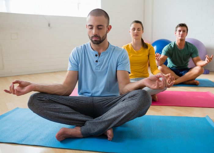 Yoga instructor with students meditating at club